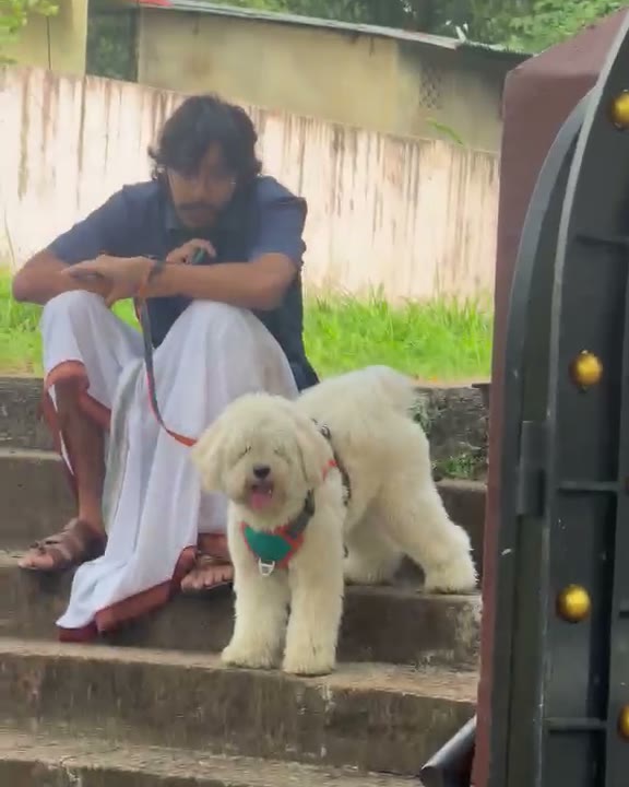Arvind and a white puppy on the front steps, both looking at the camera